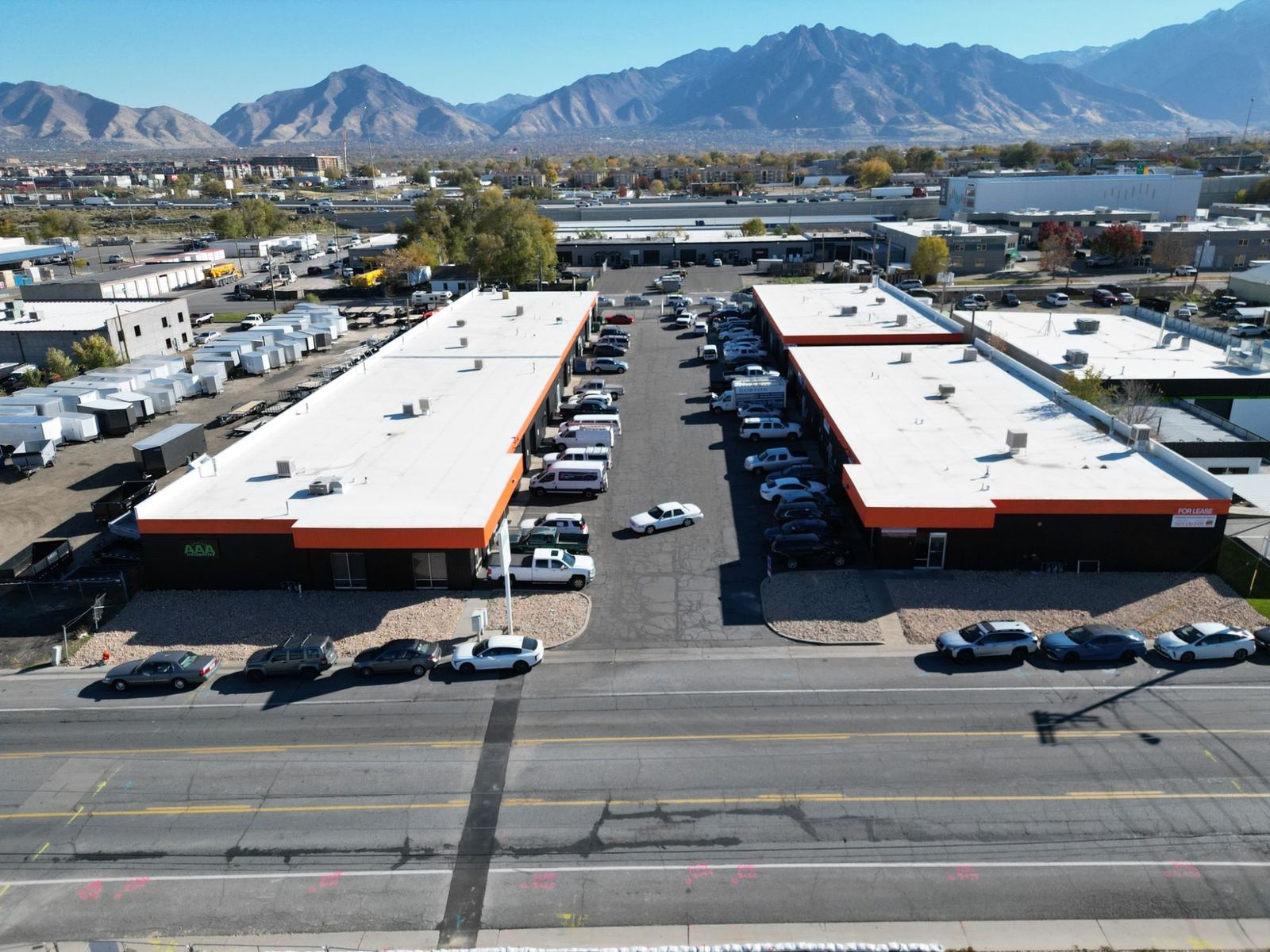 Aerial view of two single-story flex industrial buildings with orange trim and the Wasatch Mountains behind