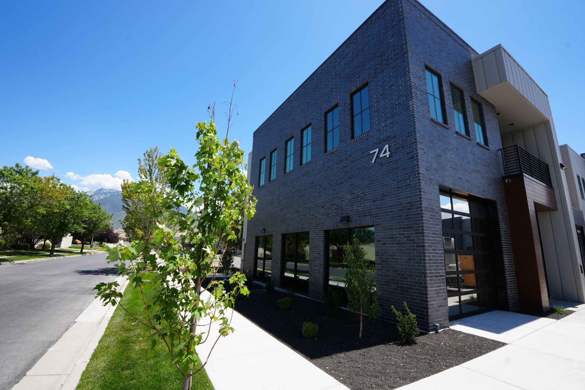 Modern dark brick two-story commercial building with mountains in the distance