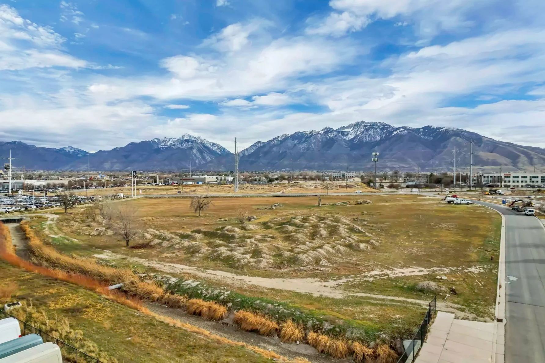 Open commercial land with the snow-capped Wasatch Mountains behind